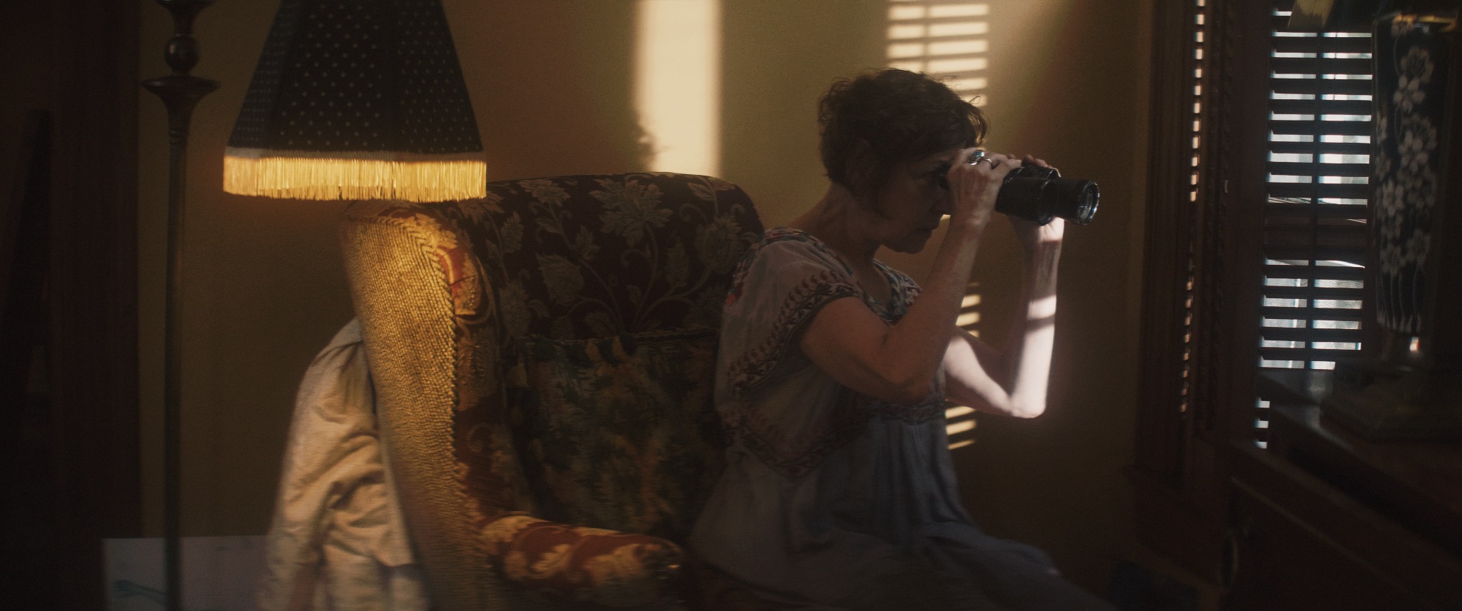 Iris looks out the window through binoculars